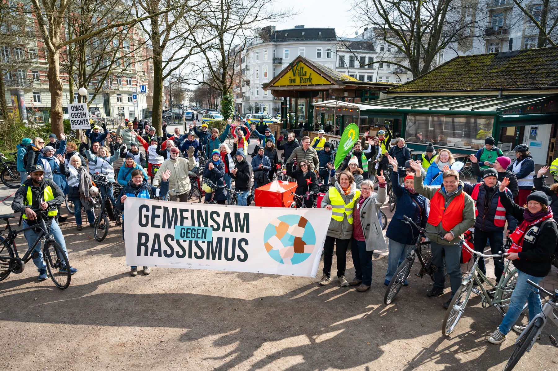 Teilnehmende einer Fahrraddemonstration halten ein Banner mit der Aufschrift ‚Gemeinsam gegen Rassismus‘.